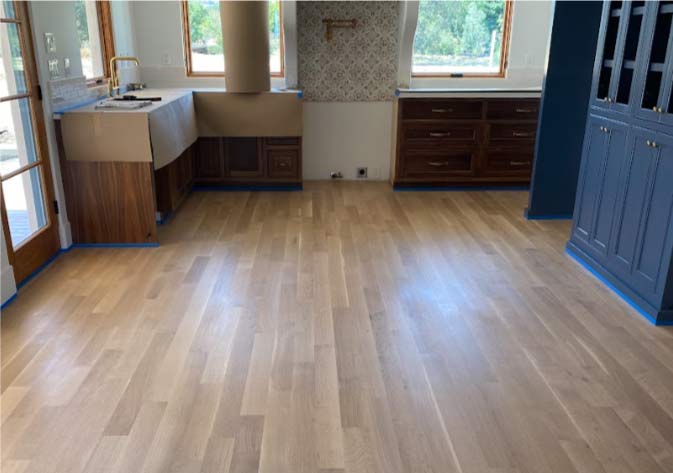 Close-up of high-quality hardwood floor texture and finish, emphasizing the material cost investment and long-term durability.