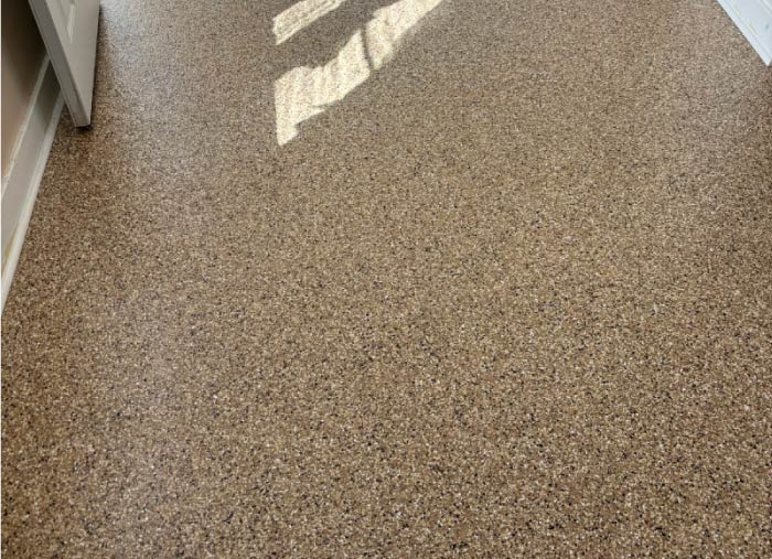 Durable, textured brown and black flake epoxy flooring applied to an indoor residential entryway