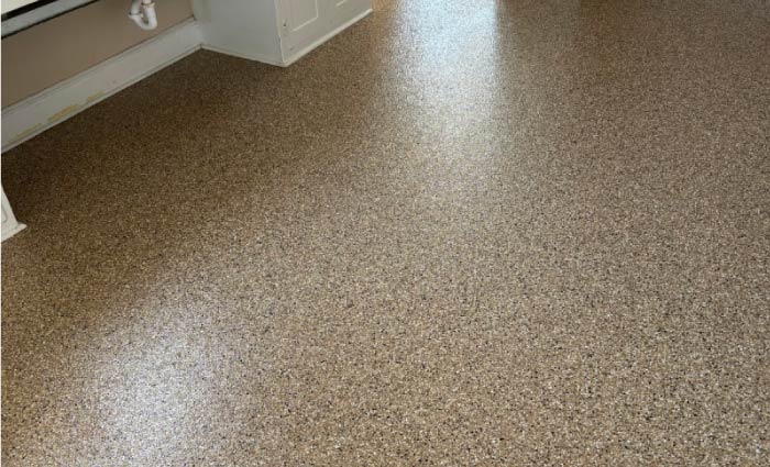 Seamless, shiny brown flake epoxy coating extending from a kitchen or laundry room into a garage