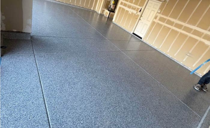 New gray epoxy flake floor with control joint lines, professionally installed in a clean, modern garage space
