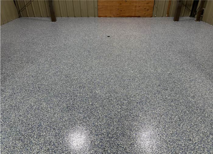 Wide view of a spacious garage floor with a decorative blue and gray flake epoxy flooring finish and glossy sealant