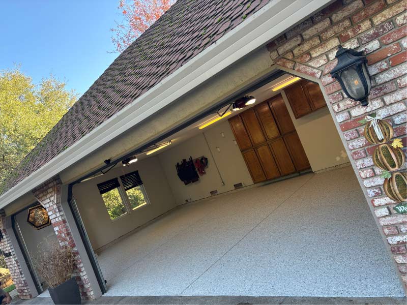 Finished multi-car garage in Sacramento featuring a high-gloss grey flake epoxy floor coating with professional brick masonry exterior and clean white interior walls.