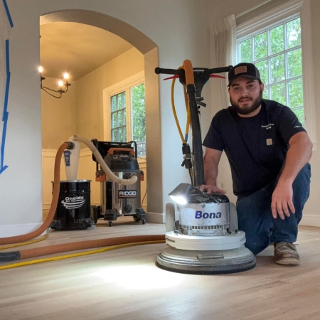 Owner Guadalupe Ortiz of Sacramento Valley Flooring using a professional Bona sander and HEPA-filtered dust containment system for a clean, dustless wood flooring project.