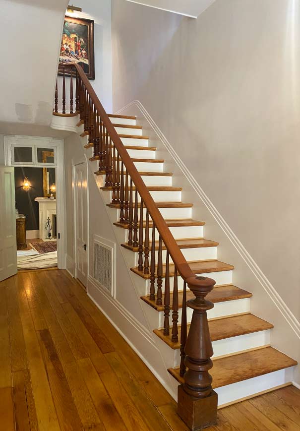 Final result of a custom wood staircase installation with matching hardwood flooring, highlighting elite craftsmanship and elegant balusters.