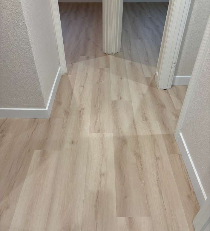 Professional vinyl flooring installation in a Sacramento home hallway, showing light oak-style luxury vinyl planks with clean white baseboards and precise transitions between doorways