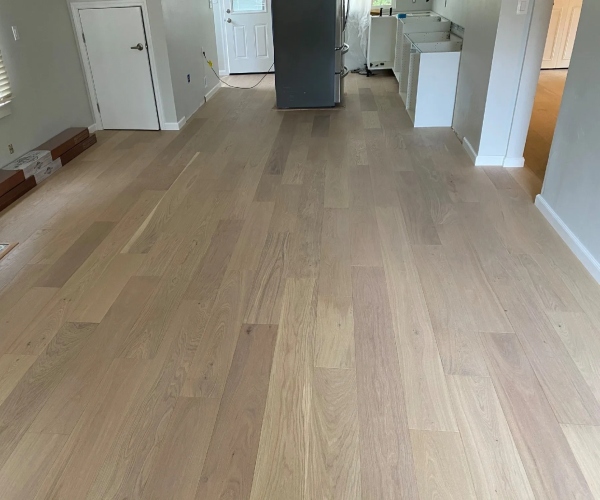 Professional installation of wide-plank light oak wood flooring in a Sacramento home remodel, featuring seamless transitions and a modern matte finish.